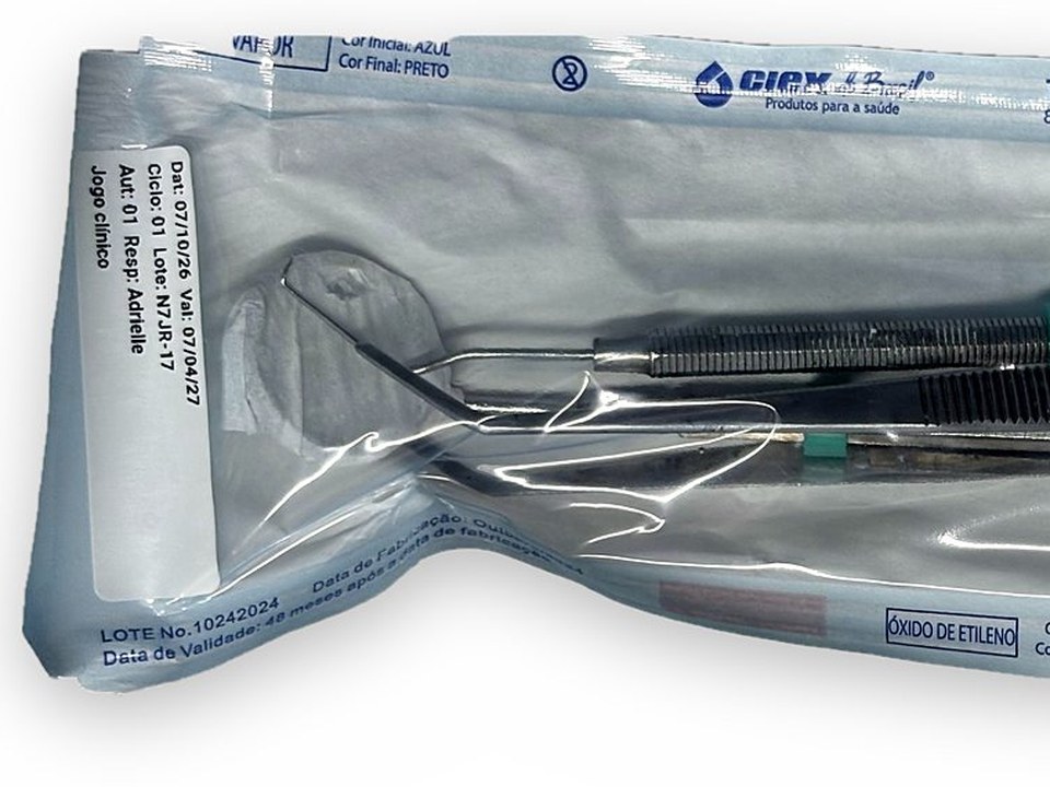Envelope de grau cirúrgico com espelho, sonda e pinça, com a etiqueta colada na face plástica.